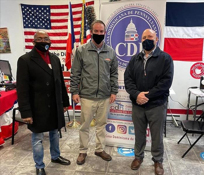 3 individuals in front of pop up sign and flags